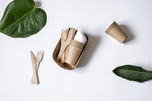 Vaisselle écologique jetable en bois de bambou et papier. Coupes, couteaux et fourchettes vue de dessus isolée.