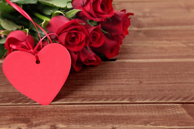 Valentine étiquette de cadeau et des roses sur planche de bois