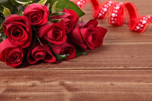 Valentine roses rouges et ruban sur planche de bois