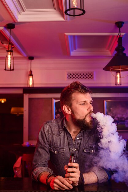 Photo gratuite vape. vaping man dans un nuage de vapeur. la photo est prise dans un bar à vape. boutique de vapotage