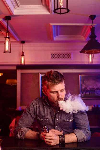 Photo gratuite vape. vaping man dans un nuage de vapeur. la photo est prise dans un bar à vape. boutique de vapotage