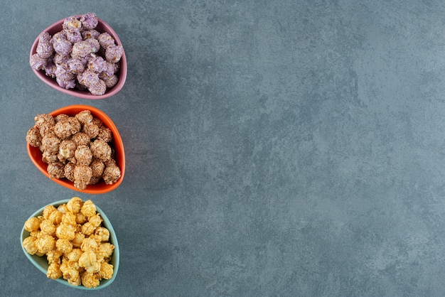 Une variété assortie de couleurs de bonbons pop-corn assorties dans de petits bols sur fond de marbre. photo de haute qualité