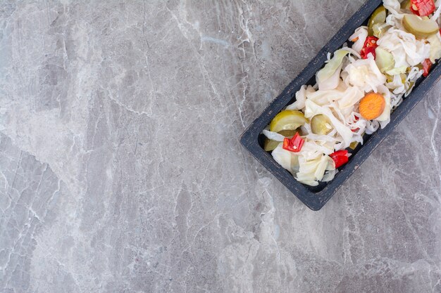 Variété de cornichons hachés sur assiette sombre.