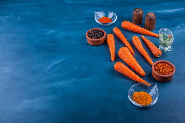 Photo gratuite variété d'épices biologiques et de carottes mûres sur une surface bleue.