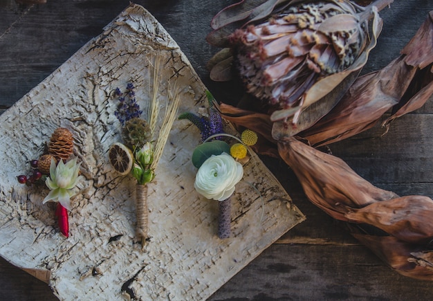 Variété d'épingles de gilet préparées avec des fruits secs et des fleurs de saison symboliques sur la table.