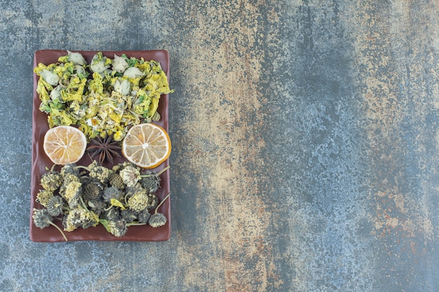 Photo gratuite variété de fleurs séchées sur plaque brune.