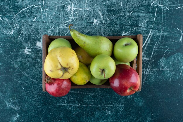 Variété de fruits savoureux dans une boîte en bois.