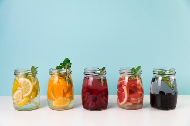 Variété de jus de fruits frais avec un fond bleu clair