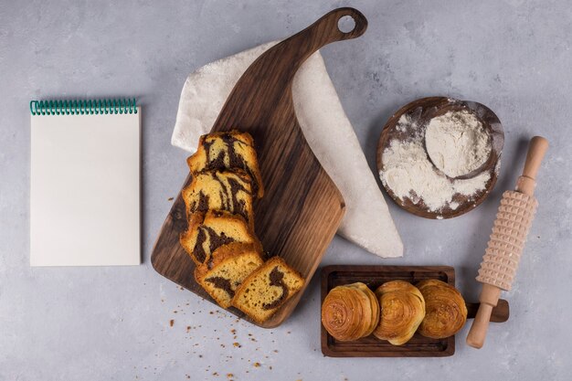 Variété de pâtisseries et craquelins sur une planche en bois avec un livre de cuisine de côté