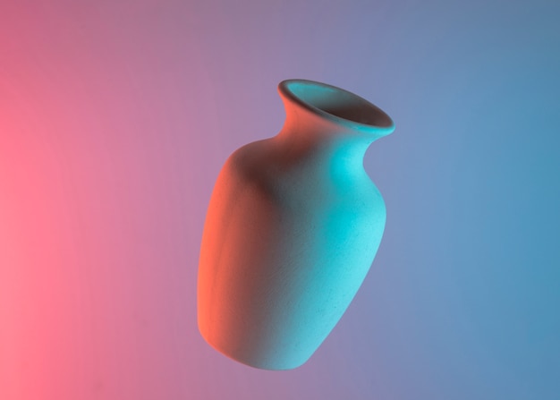 Vase blanc en céramique dans l&#39;air sur un fond coloré de bleu et de rose