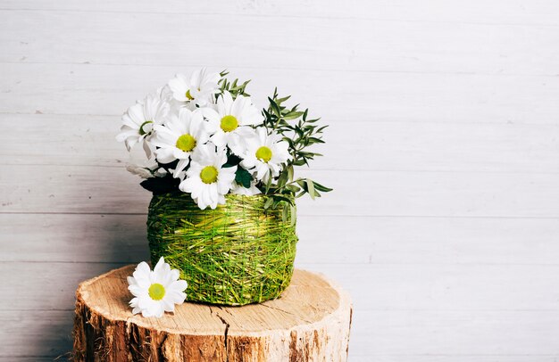 Vase à fleur blanche sur une souche d&#39;arbre sur fond en bois