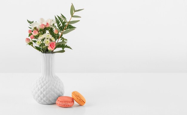 Vase avec fleurs et macarons à côté