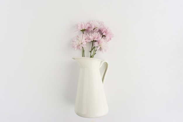 Vase avec des fleurs sur la surface blanche