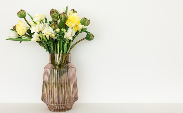 Photo gratuite vase en verre avec des fleurs à l'intérieur de la pièce