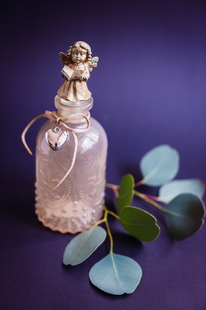 Photo gratuite vase en verre original avec ange sur le dessus et branche verte