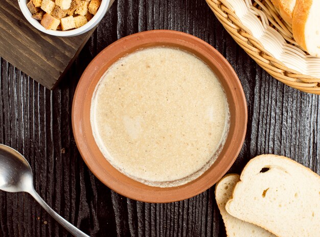 Velouté de champignons dans un bol en poterie avec des craquelins au pain.