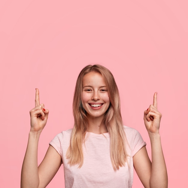 Le vendeur féminin adorable positif garde les doigts antérieurs levés vers le haut