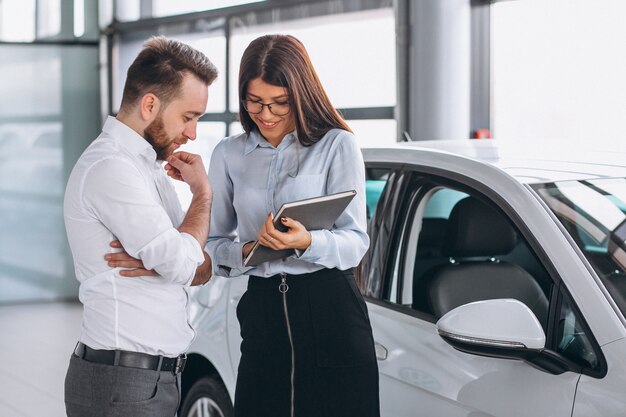 Vendeur et femme à la recherche d&#39;une voiture dans une salle d&#39;exposition