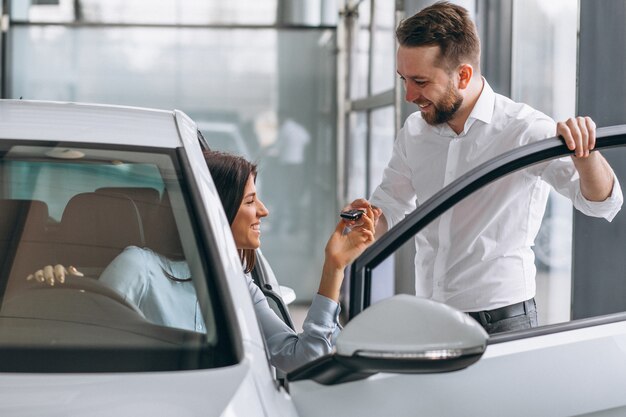 Vendeur et femme à la recherche d&#39;une voiture dans une salle d&#39;exposition