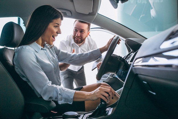 Vendeur et femme à la recherche d&#39;une voiture dans une salle d&#39;exposition