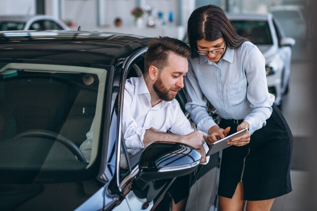 Vendeur et femme à la recherche d&#39;une voiture dans une salle d&#39;exposition