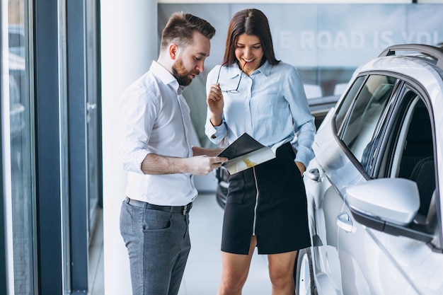 Vendeur et femme à la recherche d&#39;une voiture dans une salle d&#39;exposition