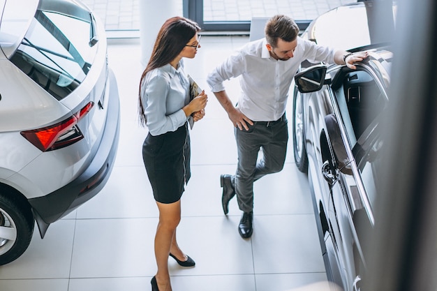 Vendeur et femme à la recherche d&#39;une voiture dans une salle d&#39;exposition