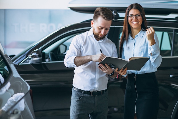 Vendeur et femme à la recherche d&#39;une voiture dans une salle d&#39;exposition