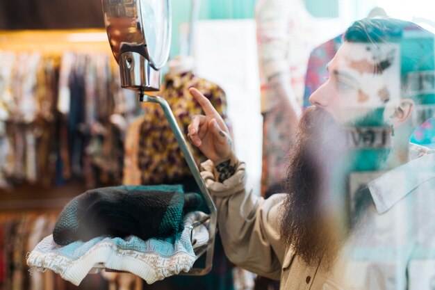 Vendeur masculin vérifiant le poids du tissu sur des balances à la boutique de vêtements vu à travers le verre