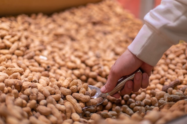 Vendeur prenant des arachides dans des coquilles au marché. Photo de haute qualité