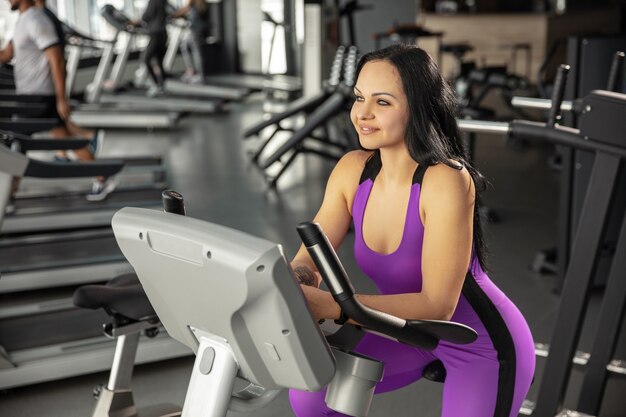 A venir. Jeune femme caucasienne musclée pratiquant dans la salle de gym avec cardio. Modèle féminin athlétique faisant des exercices de vitesse, entraînant le bas du haut du corps. Bien-être, mode de vie sain, musculation.