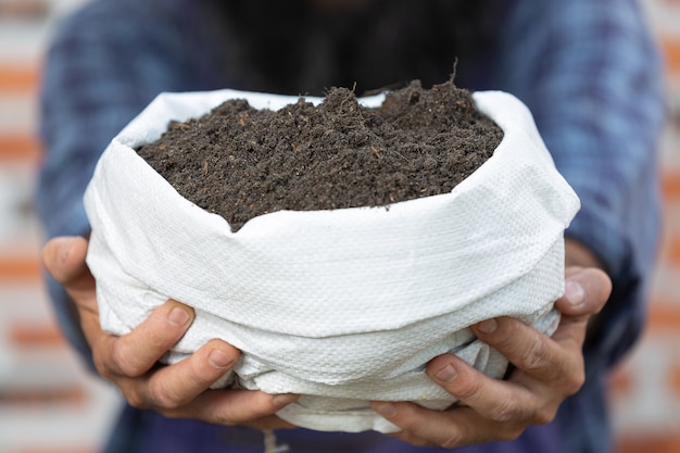 Photo gratuite vente de plantes en ligne; gros plan de la main tenant un sac de terre