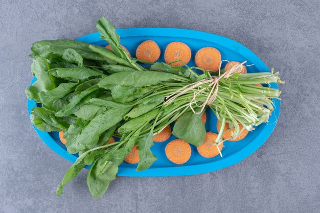 Verdure avec carottes tranchées sur le plateau, sur la surface en marbre.