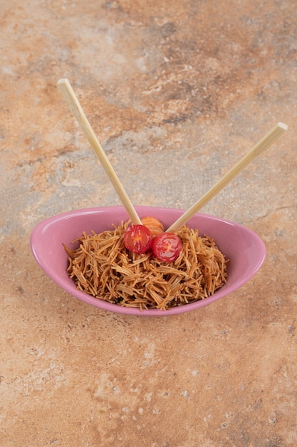 Photo gratuite vermicelles frits à la tomate dans un bol rose avec des baguettes