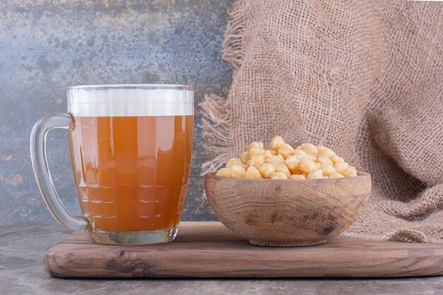 Verre de bière et bol de petits pois sur planche de bois. photo de haute qualité