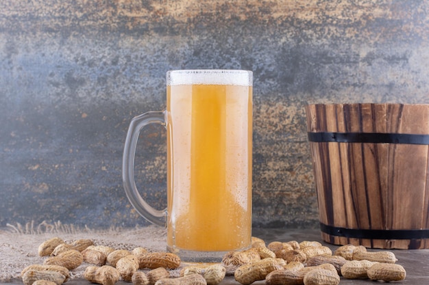 Verre de bière et cacahuètes éparpillées sur table en marbre