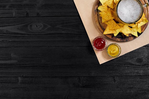 Verre de bière avec chips de nachos sur un fond en bois.