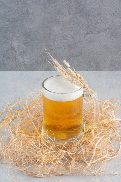 Un verre de bière délicieuse avec du blé sur du foin.