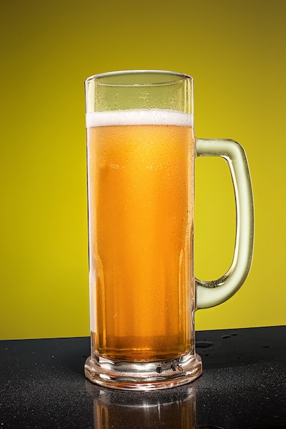 Verre de bière lager mousseuse froide sur une vieille table en bois