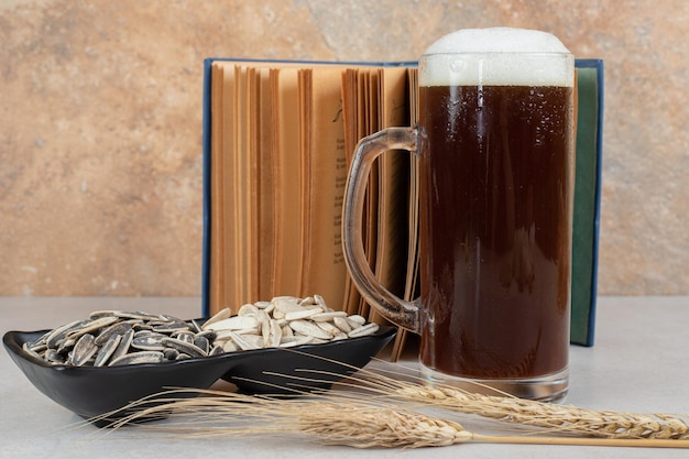 Verre de bière, livre et assiette de graines de tournesol