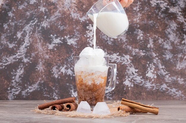 Verre avec boisson savoureuse et cannelle sur marbre.