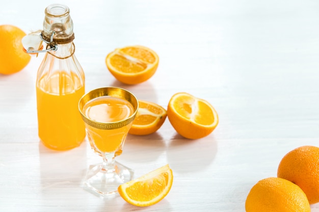 Verre et bouteille de liqueur d'orange et d'oranges crues