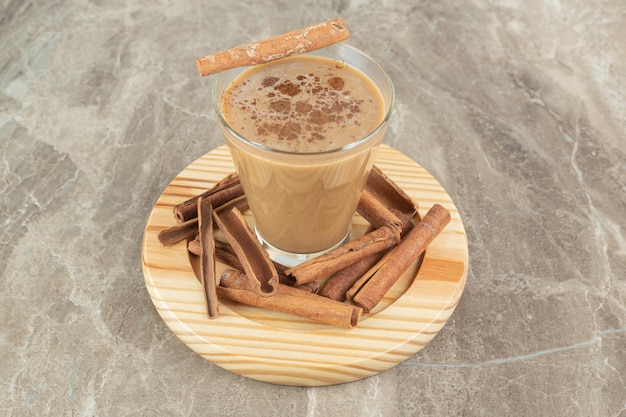 Verre de café aux cannelles sur planche de bois