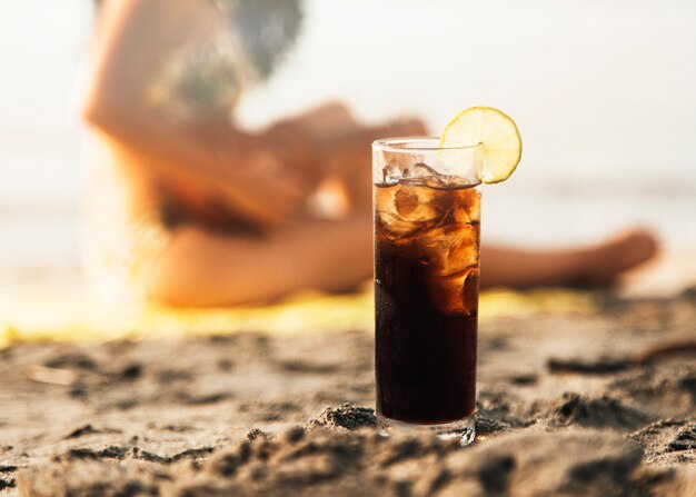 Verre de coca avec glace sur la plage