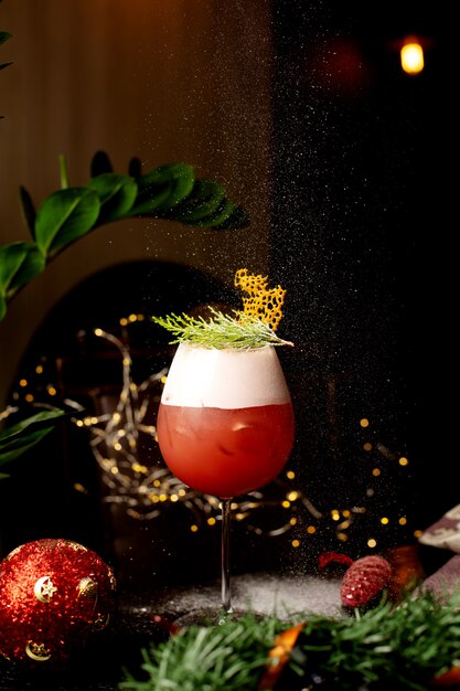 Un verre de cocktail d'agrumes garni de feuilles de pin la veille de Noël