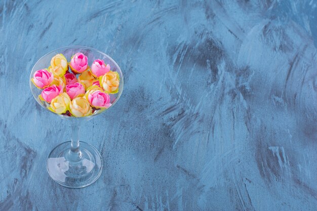 Verre à cocktail avec composition florale colorée sur bleu.