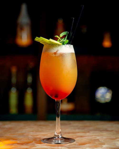 Un verre de cocktail d'orange garni de tranches de menthe et de pomme verte