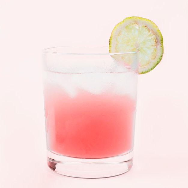 Verre de cocktail avec une tranche de citron sur fond rose