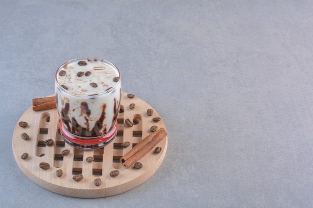Verre de délicieux café glacé avec du lait sur un outil en bois.