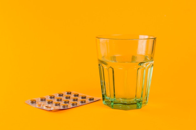 Verre d'eau avec des comprimés sur la table